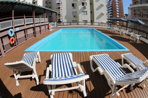 Zona de piscina con sillones de descanso y un flotador.