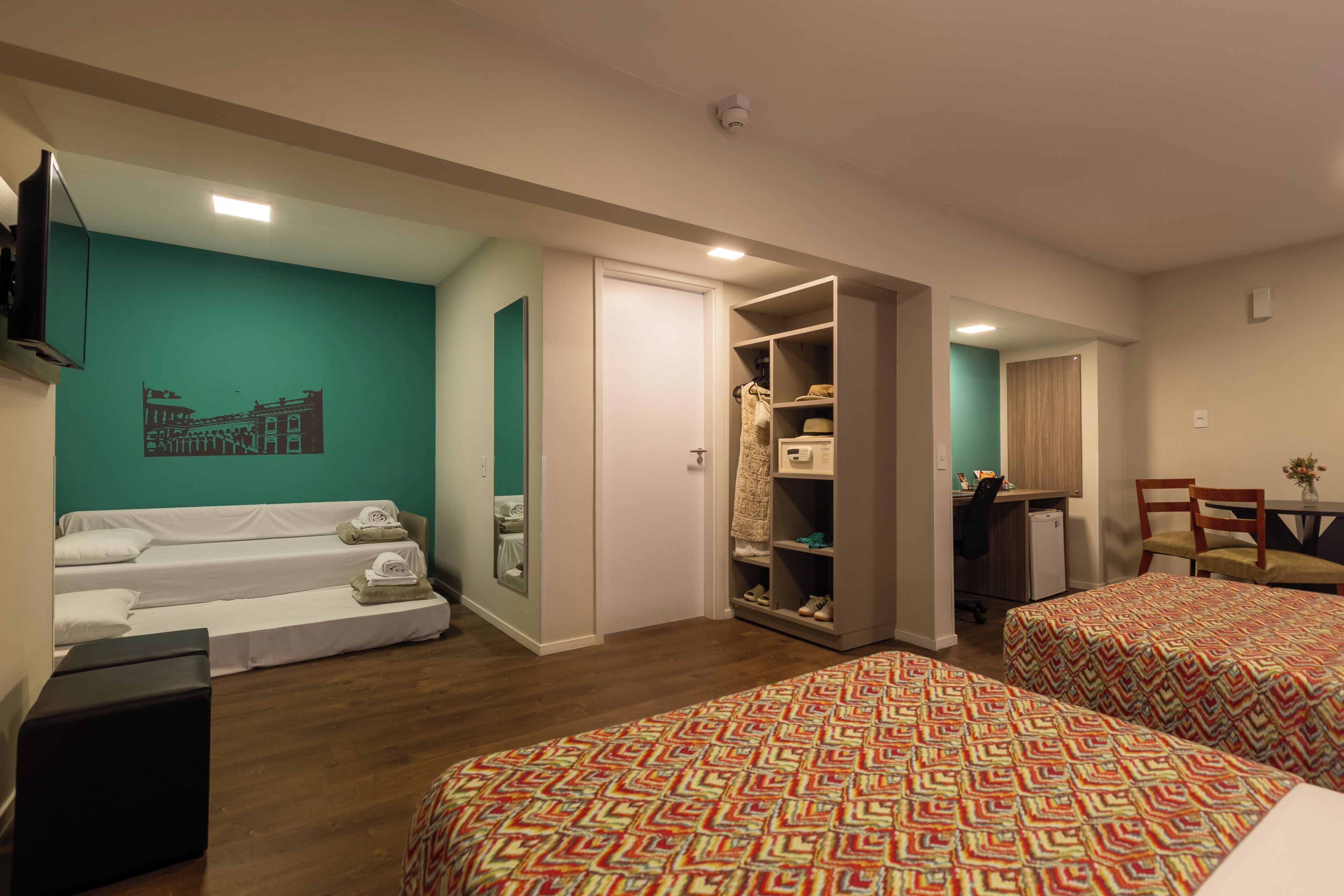 Habitación de hotel con dos camas, un sofá, un escritorio y un armario.