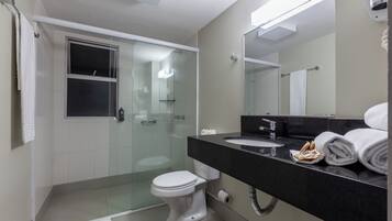 Een moderne badkamer met een douchecabine van glas, een toilet, een wastafel en een grote spiegel.