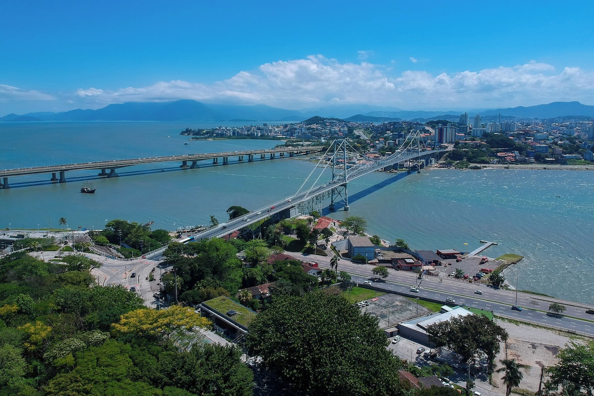 Un grand pont suspendu enjambant une large rivière, avec une vue sur la ville et la végétation au premier plan.