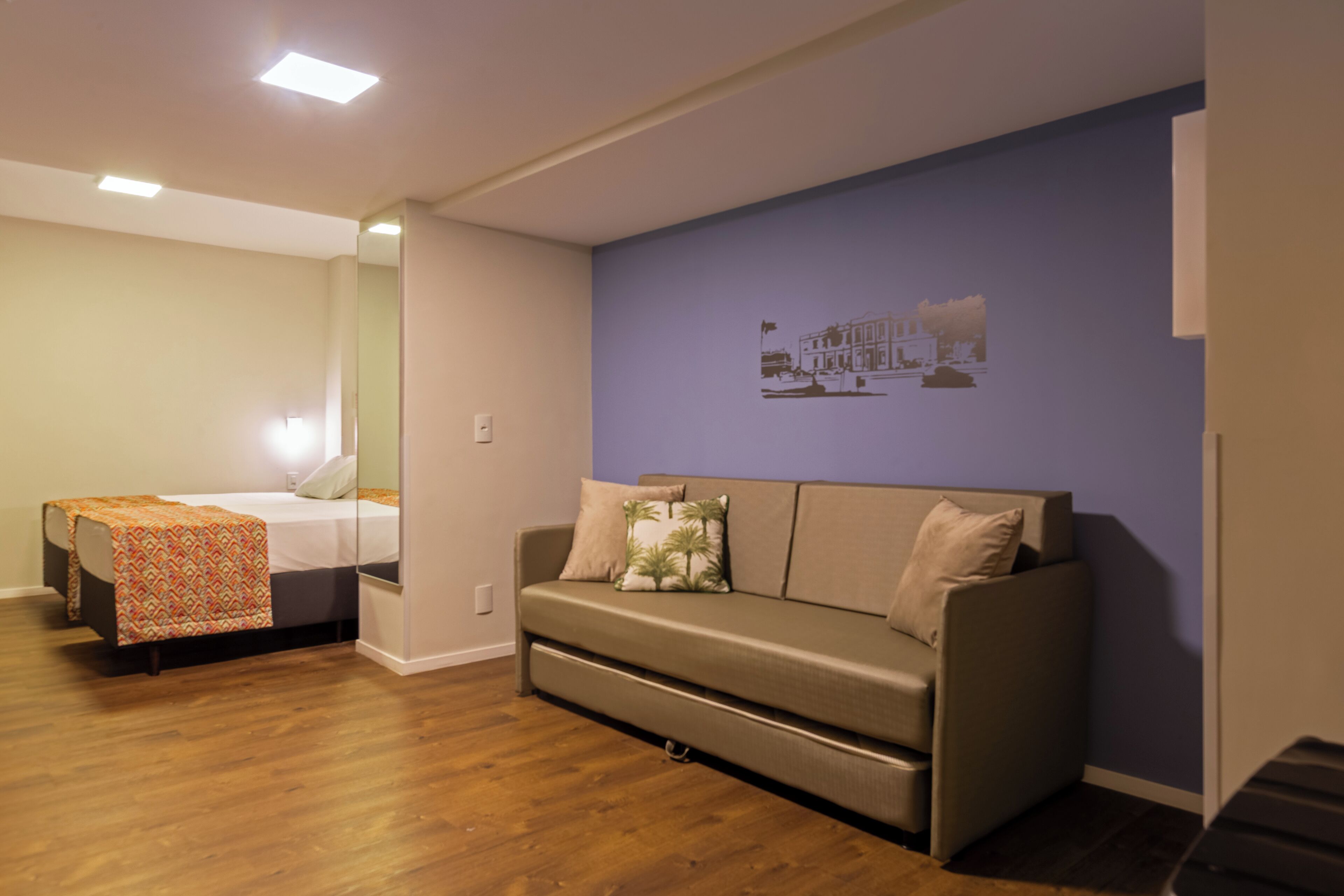Una habitación con una cama, un sofá y una pared con un mural.