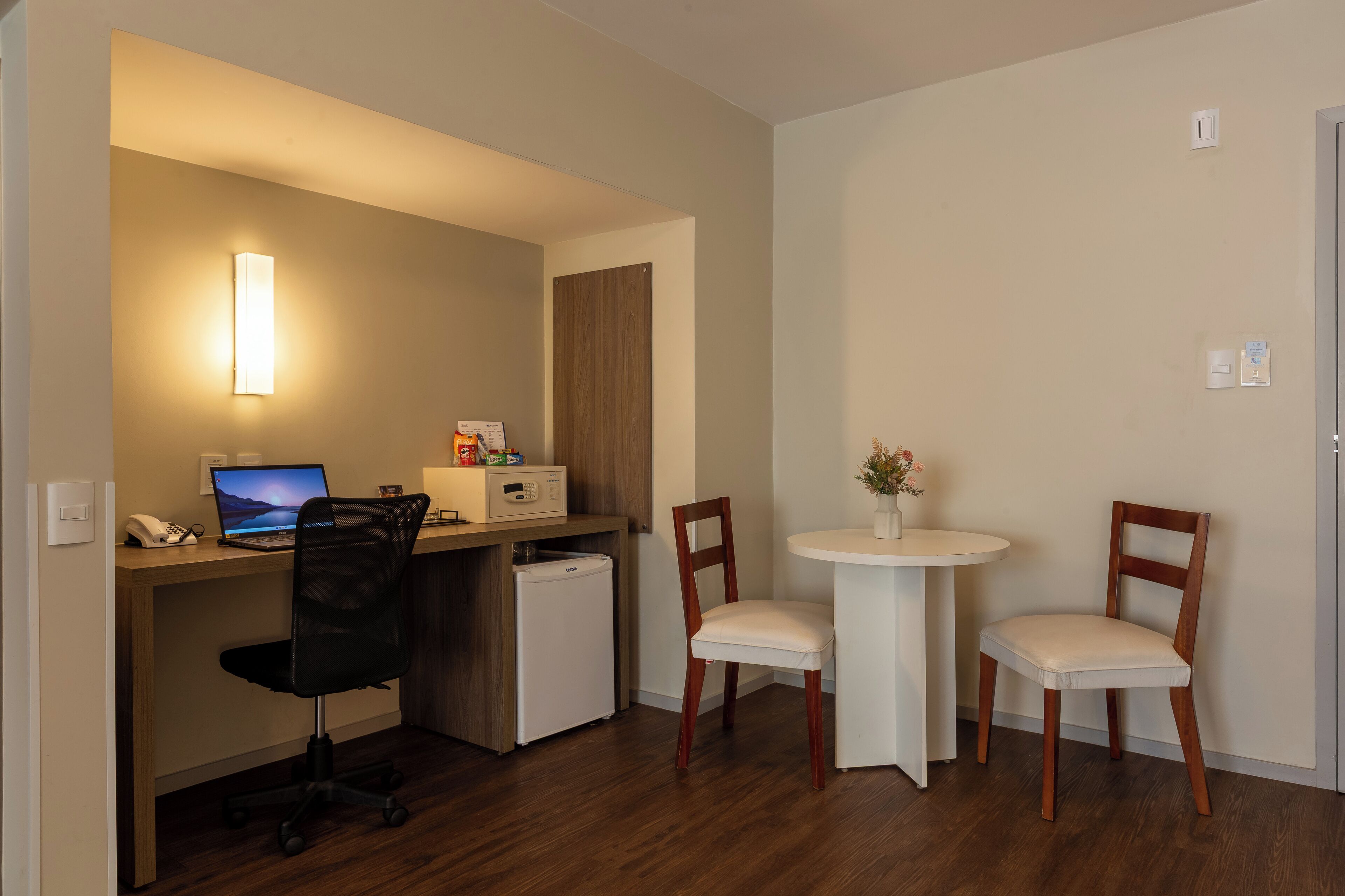 A compact office space with a desk, chair, and a small refrigerator.