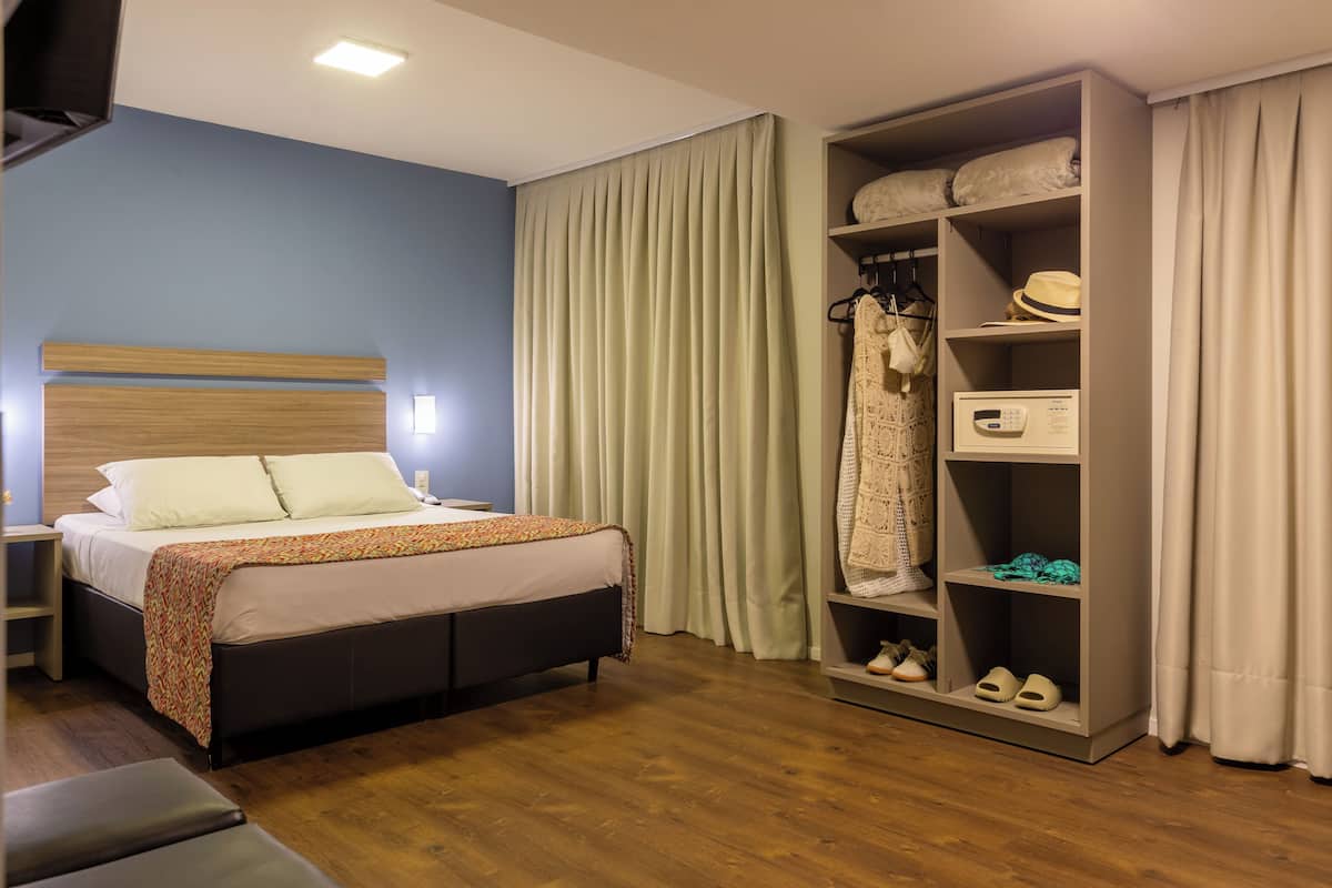 A hotel room with a bed, a wardrobe, and a shoe rack.