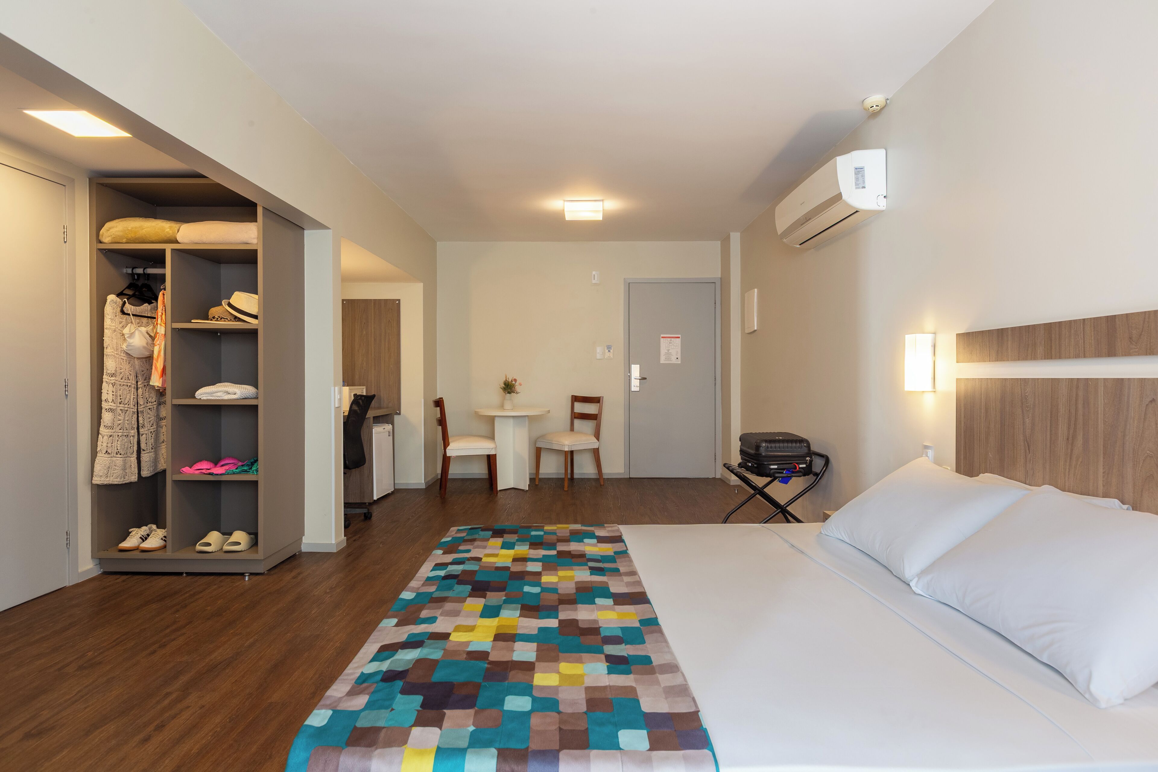 A hotel room with a bed, a closet, a desk, and a chair.