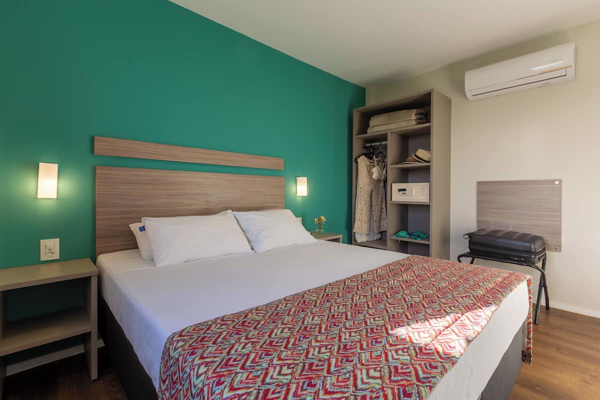A neatly made bed with a patterned bedspread, a wooden headboard, and a nightstand with a lamp.