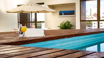 Relax by the pool with a refreshing drink in hand, surrounded by a city view.