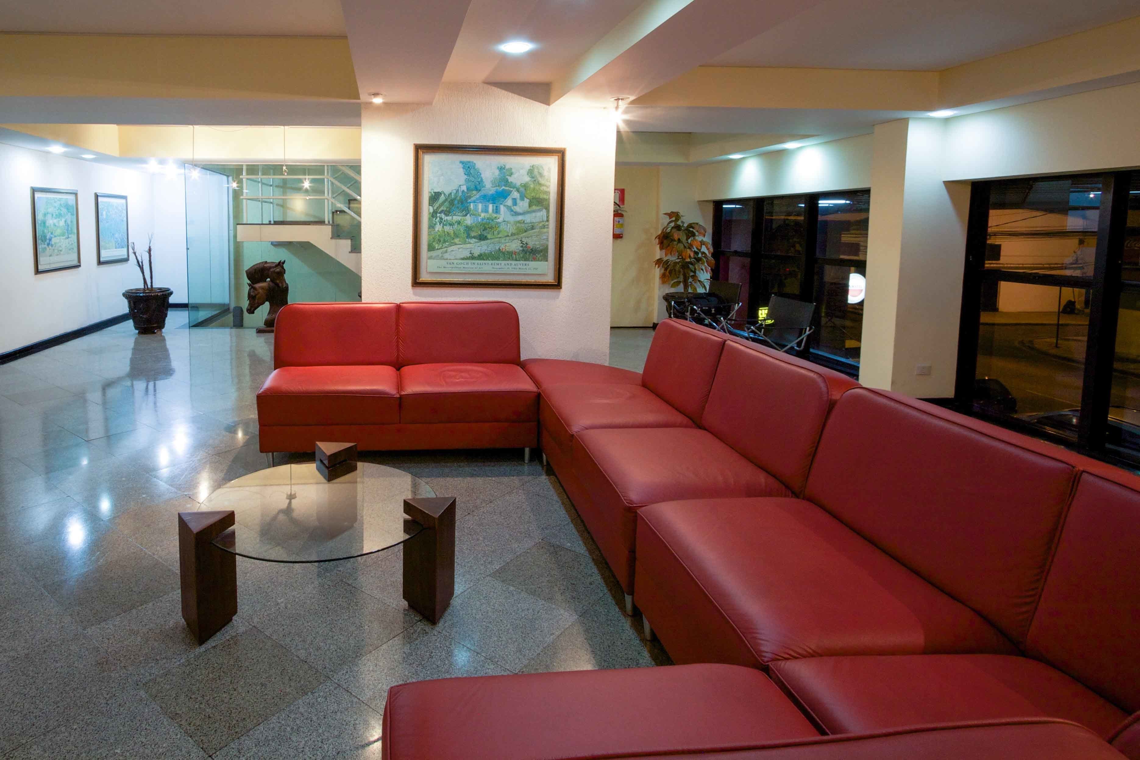 Un vestíbulo amplio con un sofá seccional rojo, una mesa de centro y una escalera al fondo.