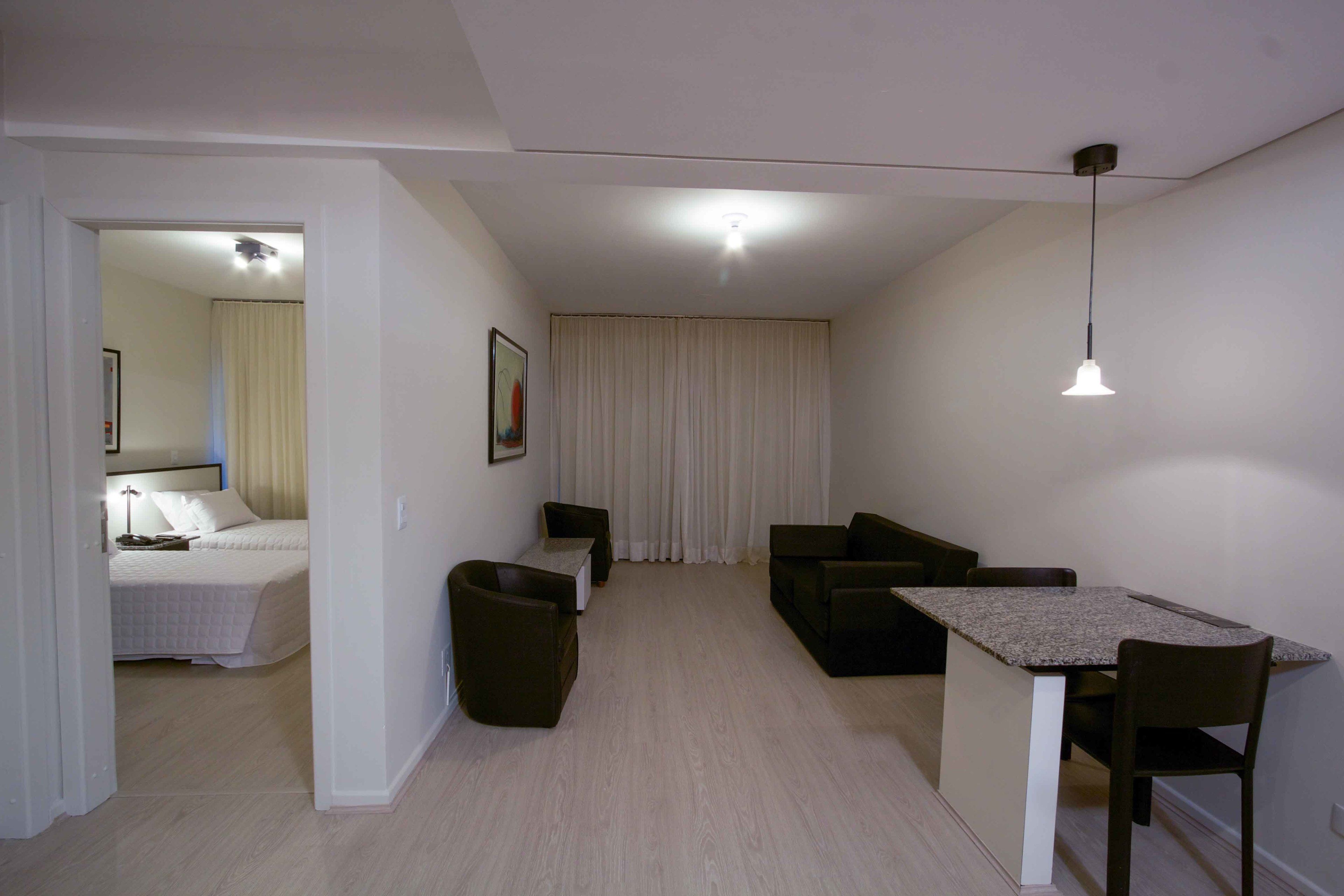 Un salón moderno y luminoso con sofá, una mesita y una cama al fondo.