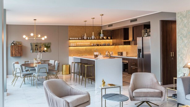 Una cocina moderna con una isla central, taburetes de bar y un comedor con una mesa redonda y sillas.