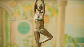 A bronze statue of a woman in a yoga pose on a pedestal.