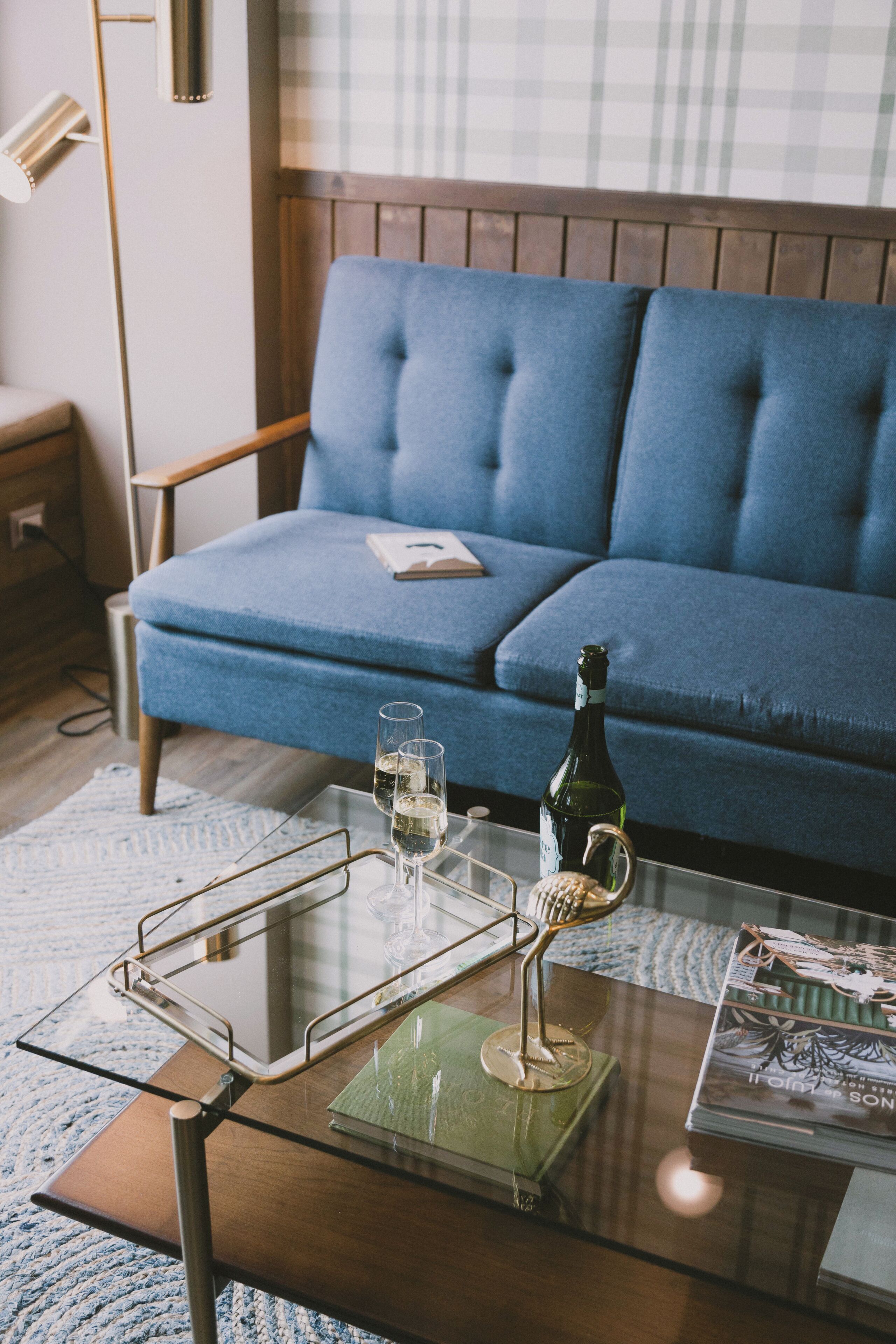 Una sala de estar moderna con un sofá azul, una mesa de centro de vidrio y una lámpara de pie.