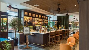 Zona de bar con mostrador, taburetes y una variedad de botellas.