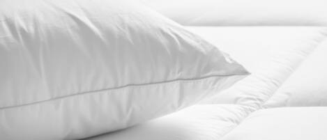 A close-up of a white bed with a neatly made pillow.