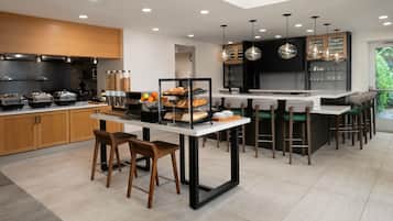 Una cocina moderna con una isla central, taburetes de bar y una barra desayunadora.