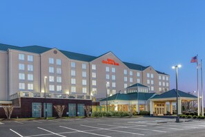 Ein großes Hotel mit einem gut sichtbaren Schild 'Hilton Garden Inn', einem Parkplatz und einem Fahnenmast mit der US-amerikanischen Flagge.