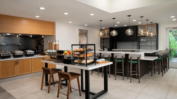Een moderne keuken met een centraal eiland, barkrukken en diverse etenswaren.