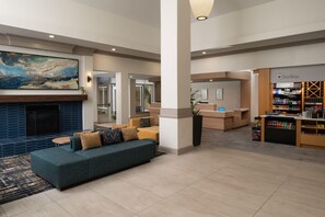Eine Hotelhalle mit einem großen abstrakten Gemälde, einem Kamin, einer Sitzecke mit Sofas, einem Empfangsbereich und einer Minibar.