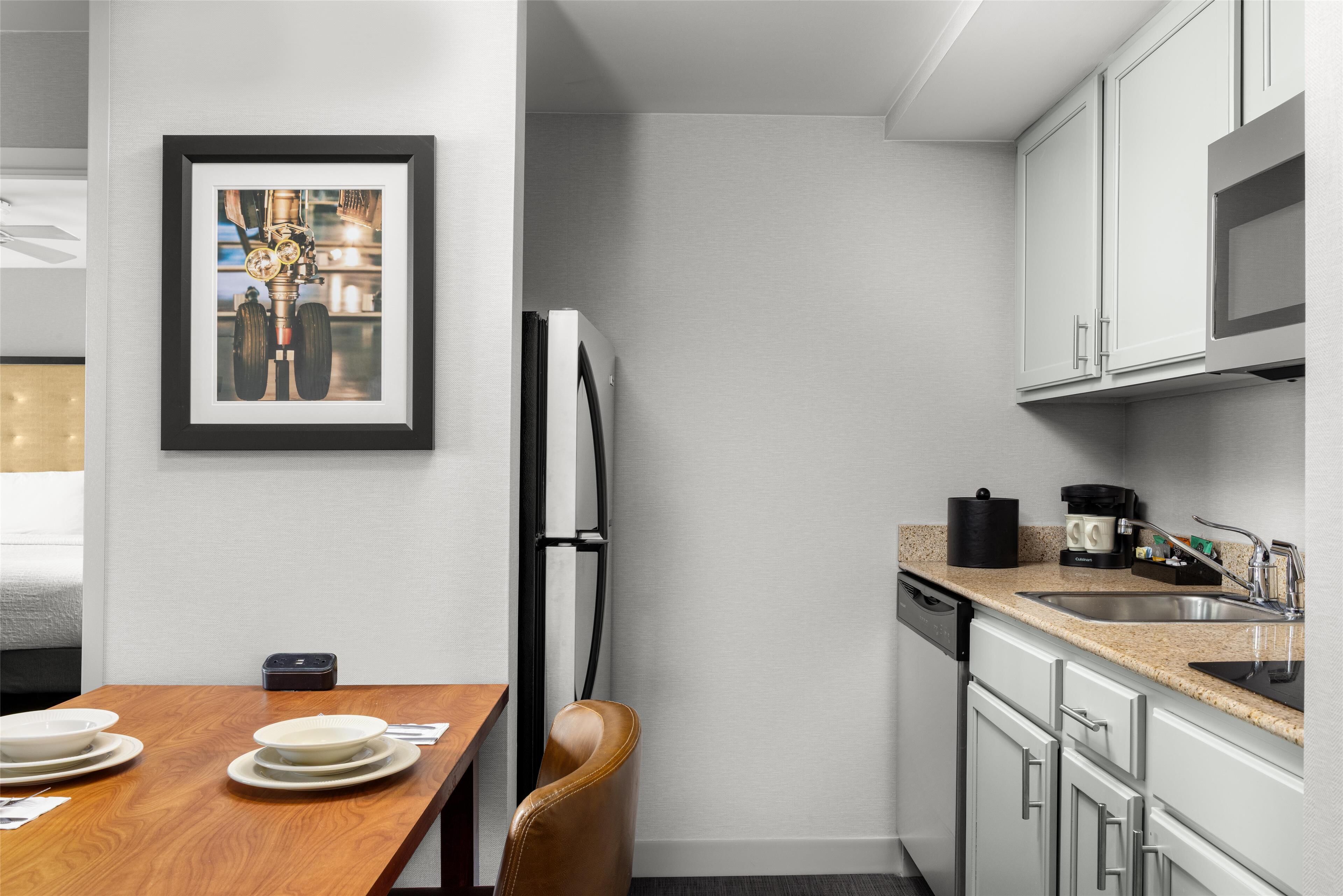 Una cocina moderna con gabinetes blancos, un lavamanos de acero inoxidable y un cuadro en la pared.