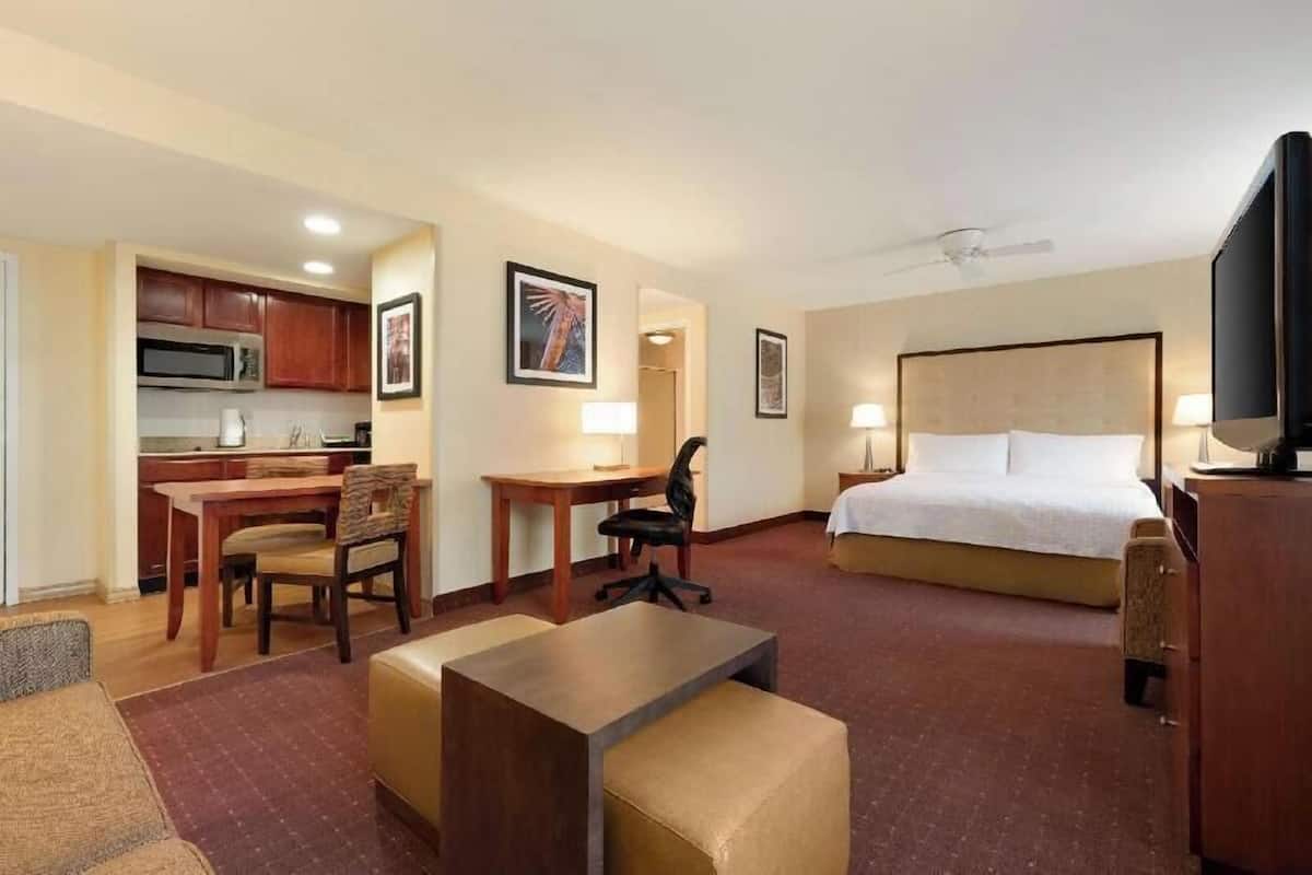Ein Hotelzimmer mit Bett, Schreibtisch, Stuhl und einer Küchenzeile.