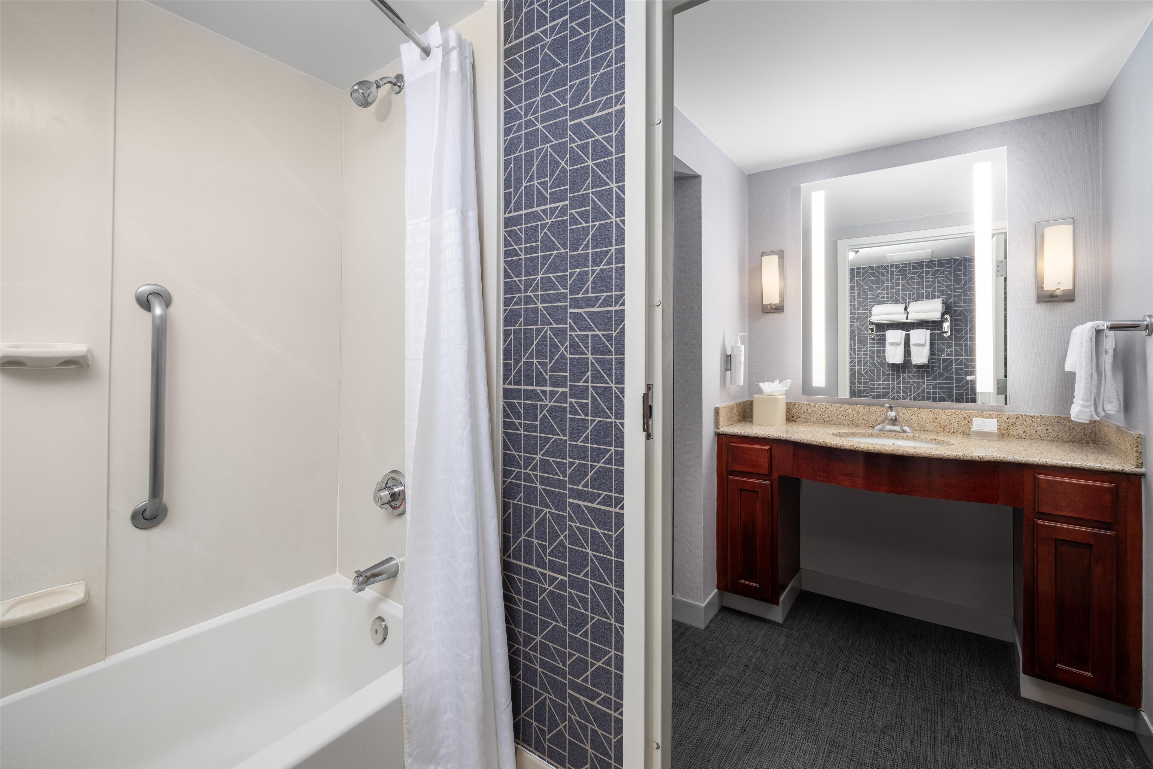 A modern bathroom with a walk-in shower, a vanity with a mirror, and a bathtub.