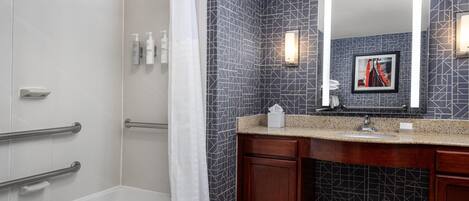A modern bathroom with a shower, a vanity with a mirror, and a tiled backsplash.