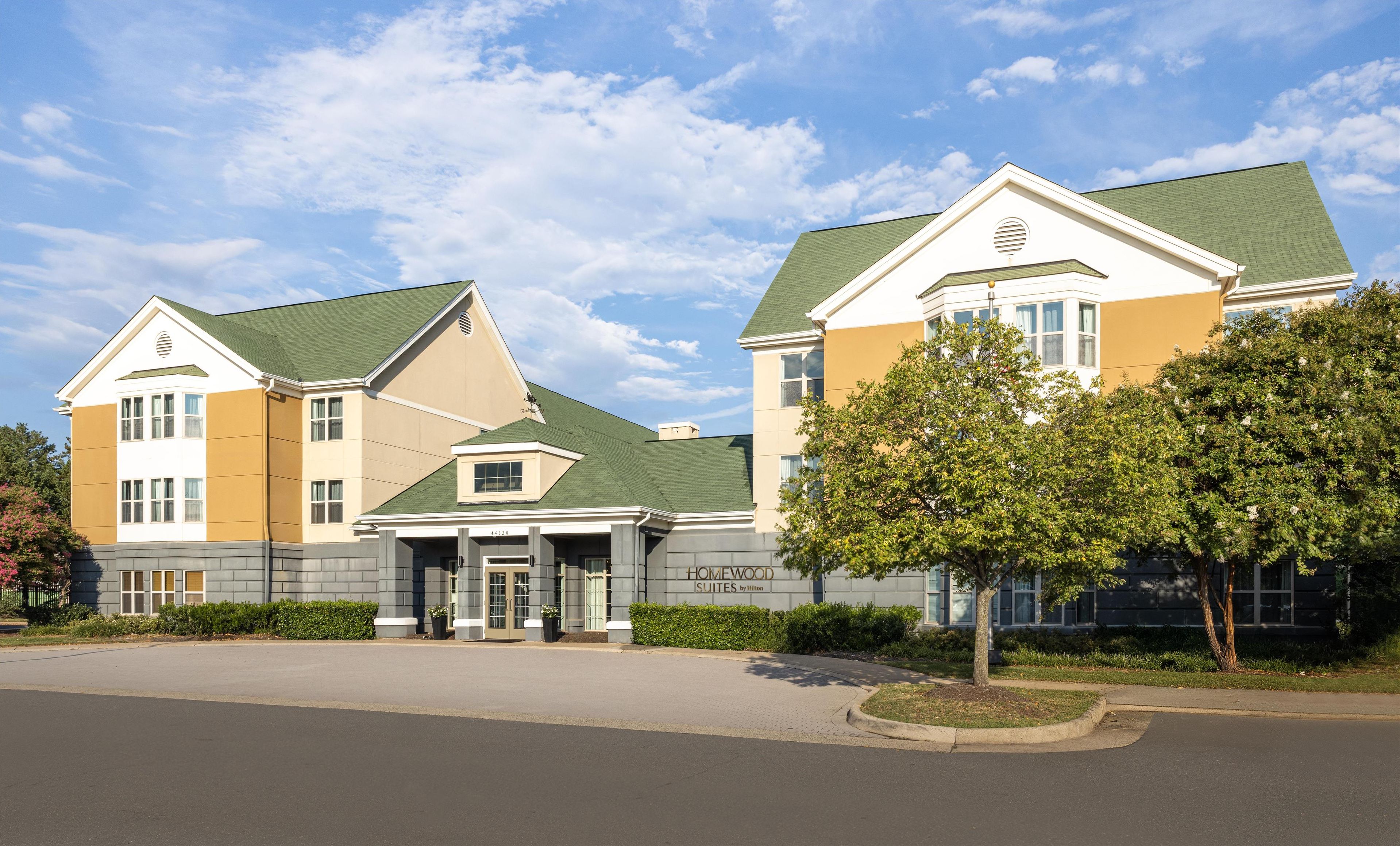 A hotel with a modern design, featuring a prominent entrance, a well-maintained lawn, and a clear sky.