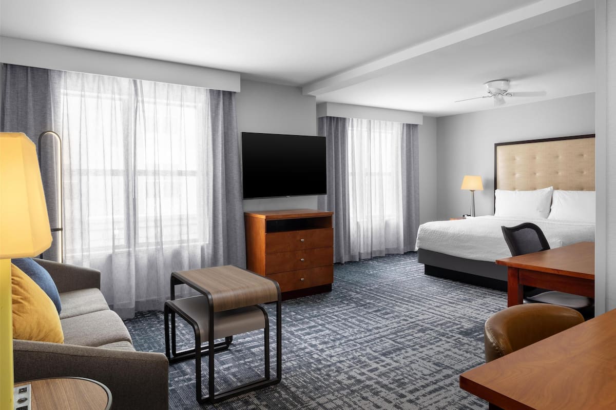 Ein Hotelzimmer mit Bett, Schreibtisch, Stuhl, Fernseher und Kommode.