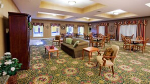 A spacious room with a patterned carpet, wooden furniture, and a large window with curtains.