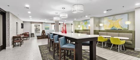A modern dining area with a long table, multiple chairs, and a seating area with a sofa and chairs.