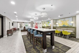 Uma sala de jantar moderna com uma mesa comprida, várias cadeiras e um espaço de estar com sofá e poltronas.