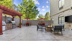 Une terrasse extérieure équipée d’un barbecue, d’un foyer et d’un espace salon.