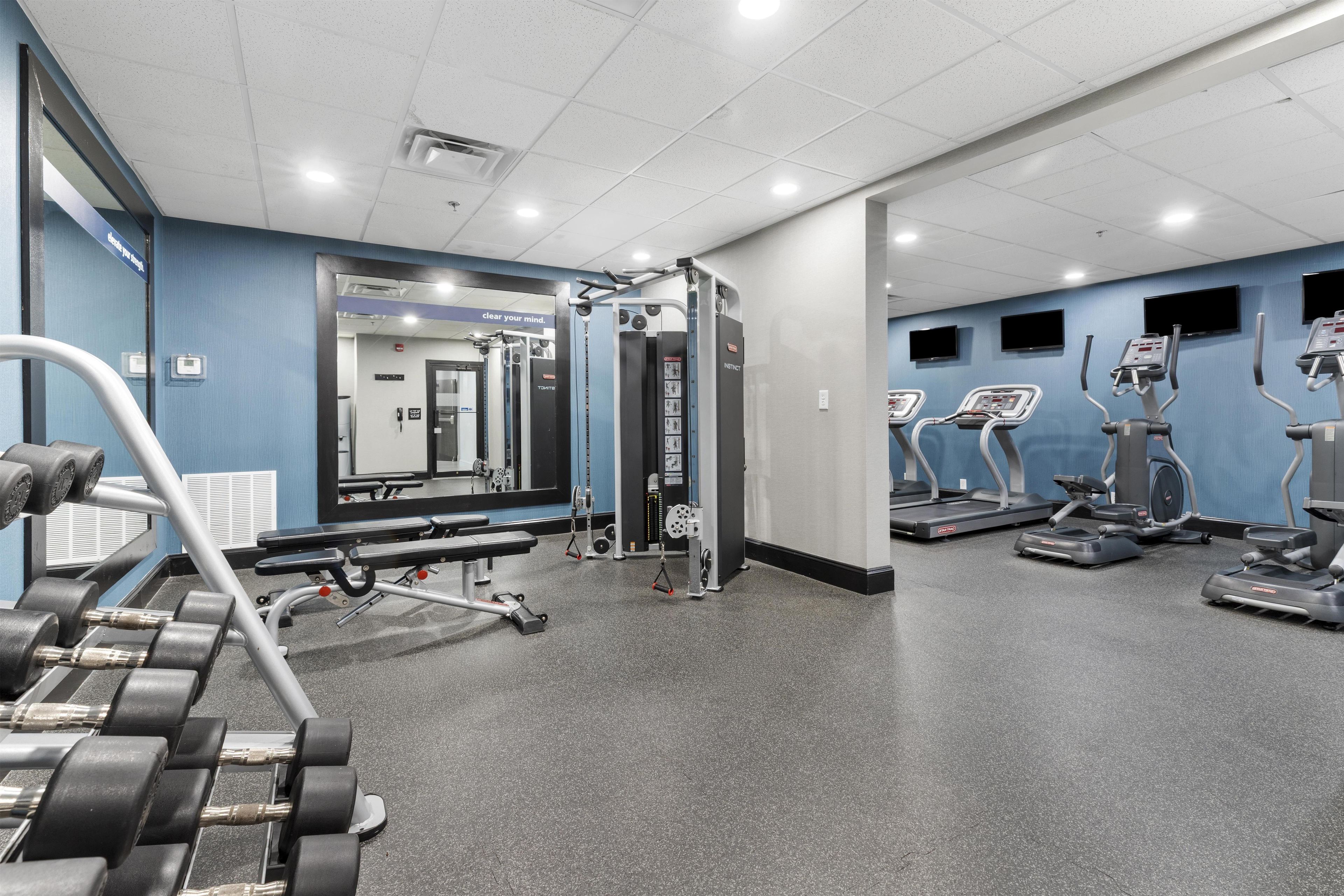 Un gimnasio con máquinas de pesas, cintas de correr y mancuernas.