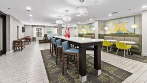 Un espace de salle à manger moderne, doté d’une longue table, de nombreuses chaises et d’un coin salon avec un canapé et des fauteuils.