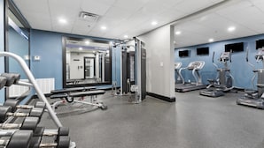 Une salle de sport équipée de machines de musculation, de tapis de course et d’haltères.