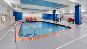 An indoor swimming pool with a blue and white color scheme, a lifeguard chair, and a pool ladder.