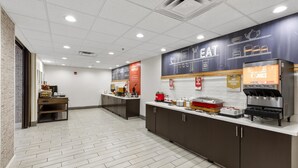 A clean, modern kitchen area with a waffle station, a juice dispenser, and a counter with various food items.