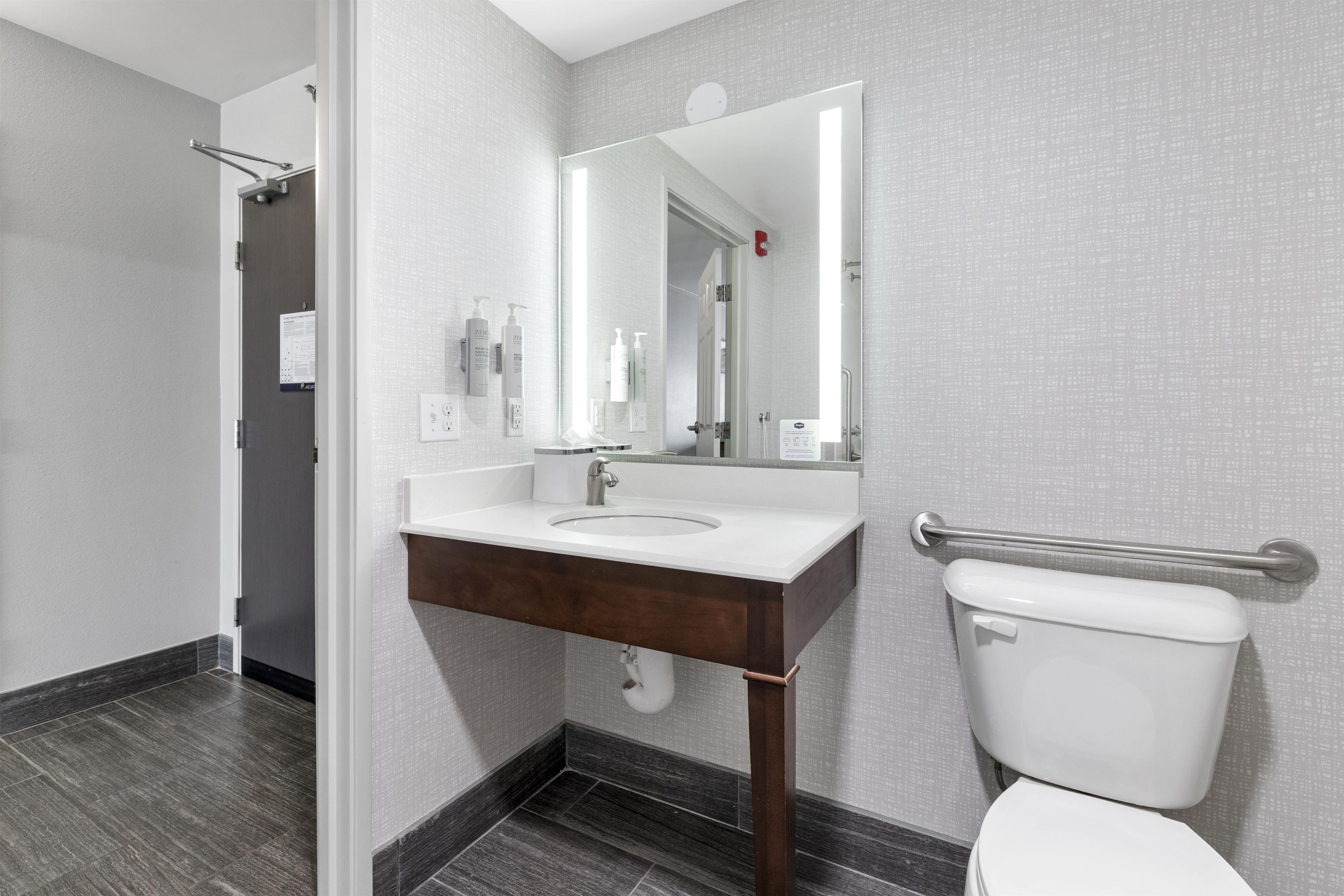 A modern bathroom with a white sink, mirror, and toilet.