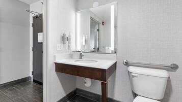 A modern bathroom with a white sink, mirror, and toilet.