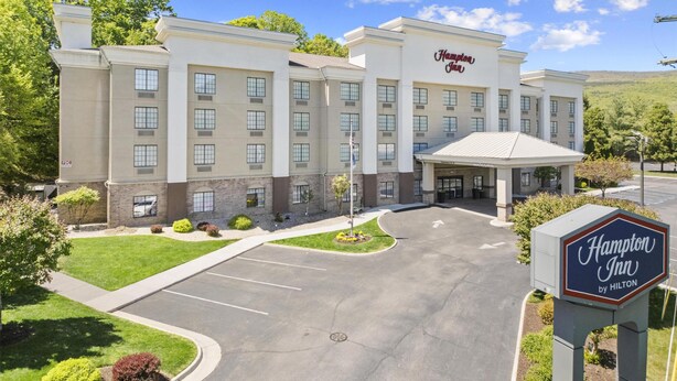 A Hampton Inn by Hilton hotel with a central courtyard, multiple entry points, and a clear sky.
