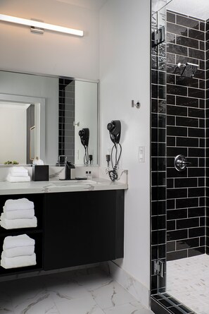 Executive suite | Badkamer | Een bad/douchecombinatie, een haardroger, handdoeken, zeep