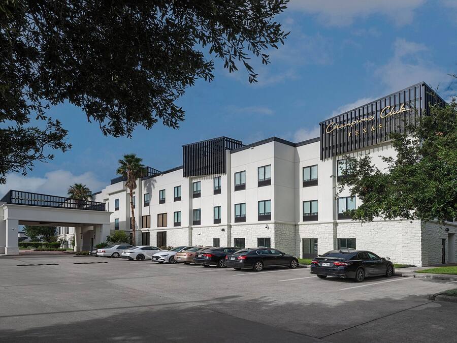 Et hotel med moderne design, med en hvid facade og et skilt der siger "Champions Club Texas".