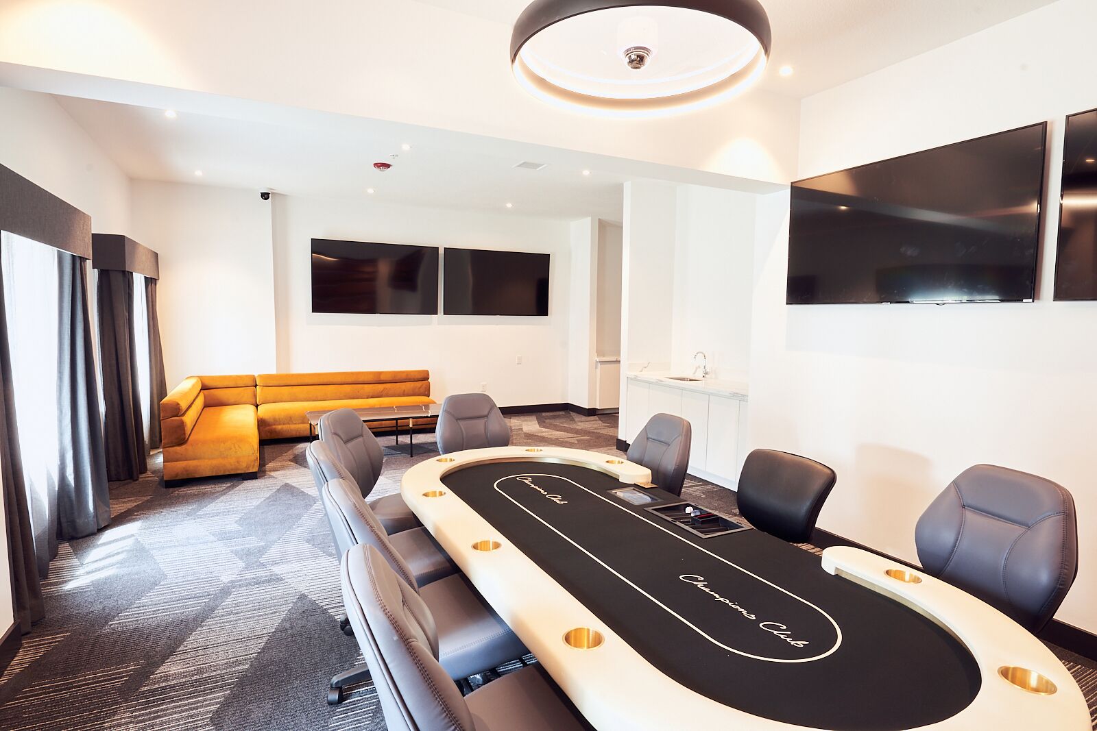 A conference room with a large oval table, a sofa, and a TV screen.