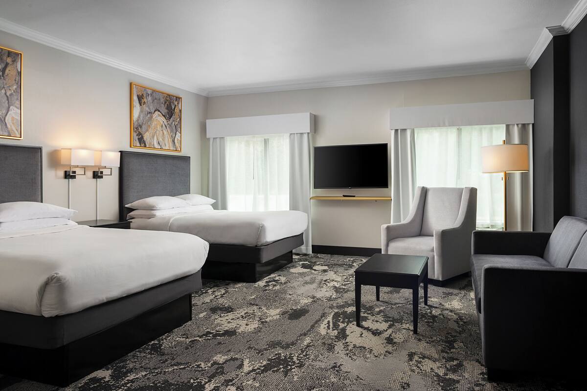 A hotel room with two beds, a TV, a sofa, and a coffee table.