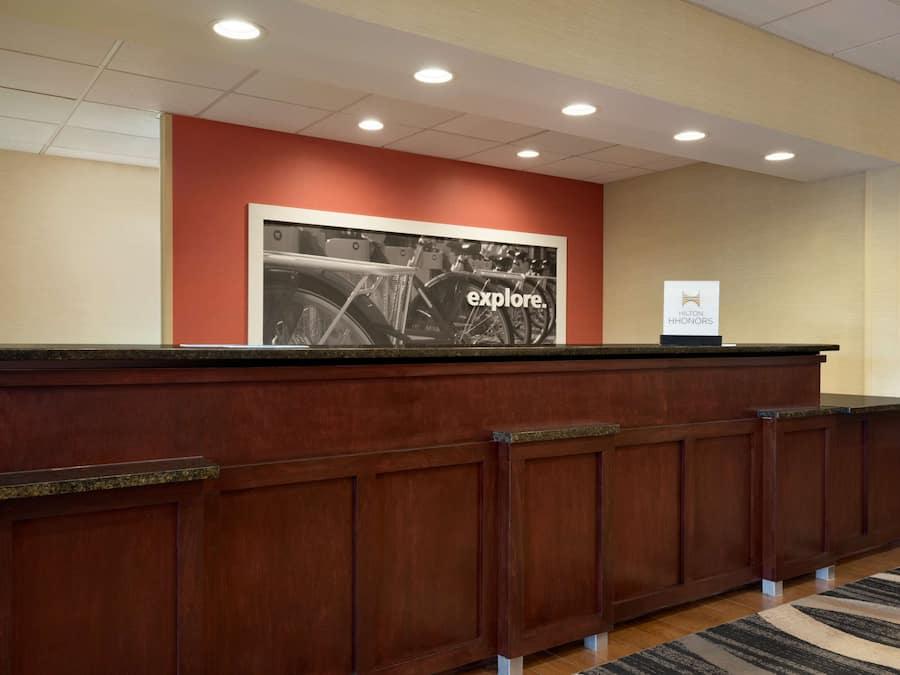 A reception desk with a large framed photo, a sign for Hilton Honors, and a carpeted floor.