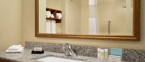 A bathroom with a granite countertop, a sink, a mirror, and a towel rack.