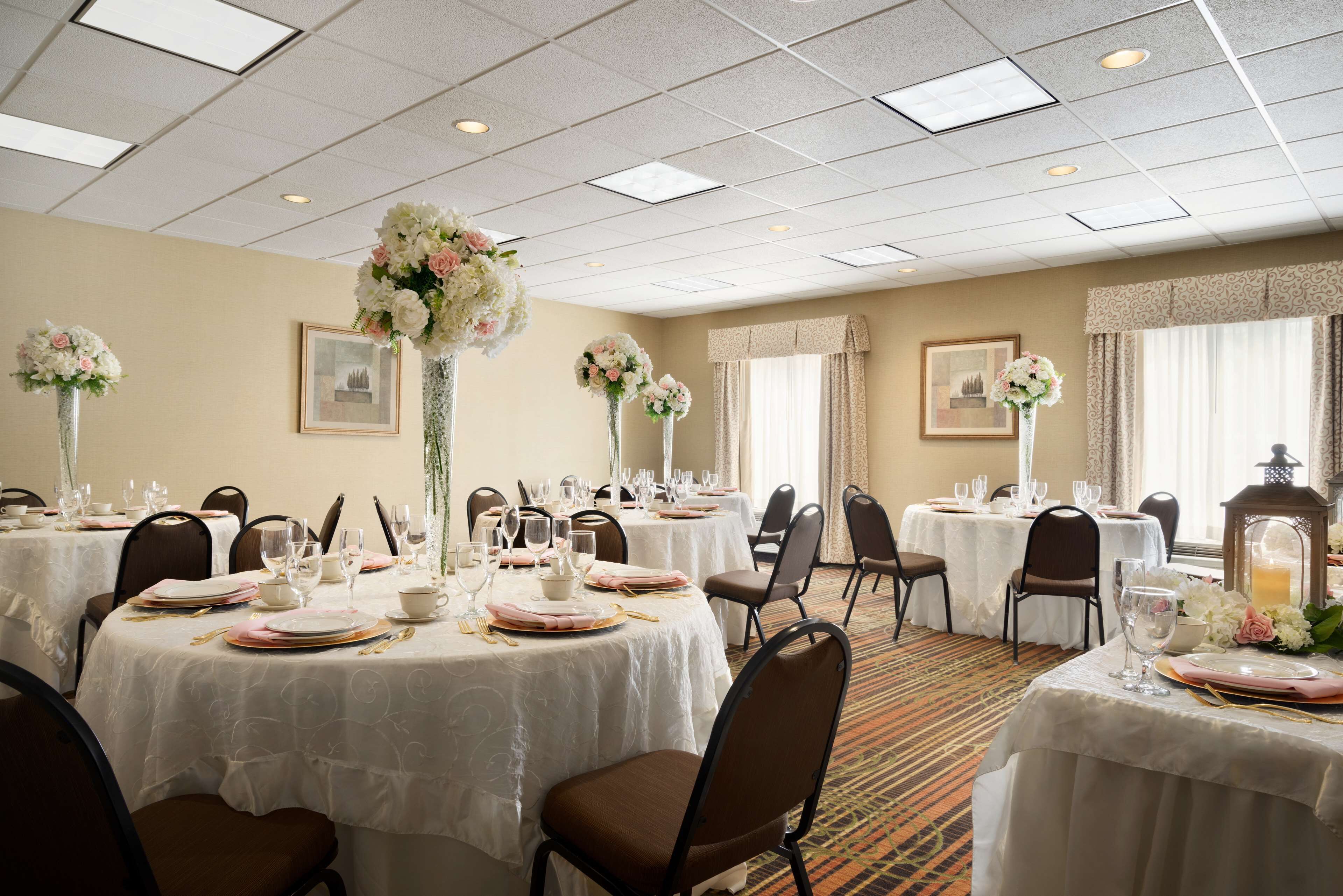 A banquet hall with round tables set for dining, featuring white tablecloths and floral centerpieces.
