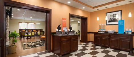 Un hall d’hôtel avec un sol à carreaux, des boiseries, un comptoir d’accueil et, au fond, un espace réservé aux repas.