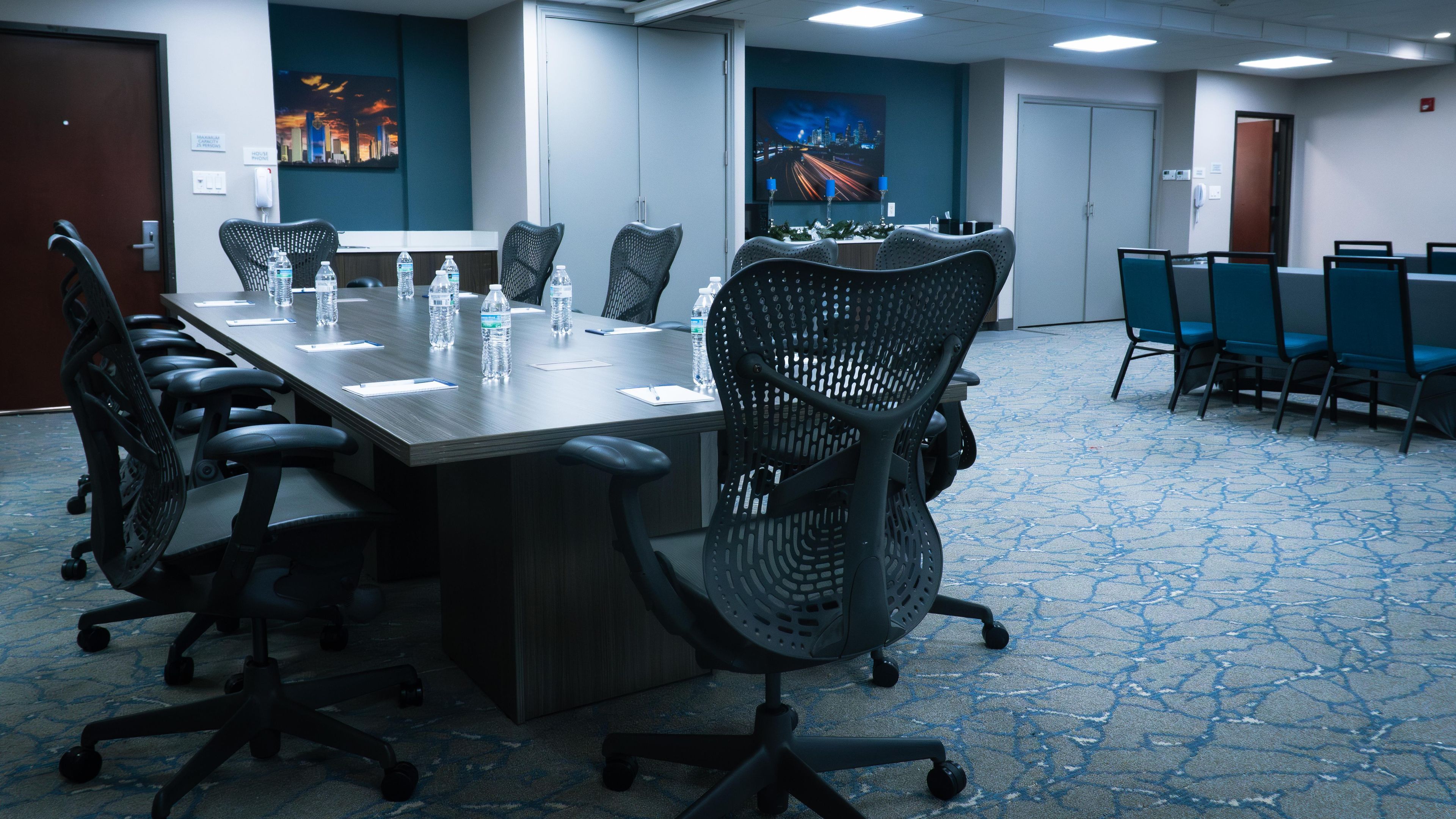 A conference room with a long table, chairs, and a carpeted floor.