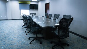 A conference room with a long table, multiple chairs, water bottles, and a TV screen on the wall. - Hampton Inn & Suites Houston Katy (Katy)
