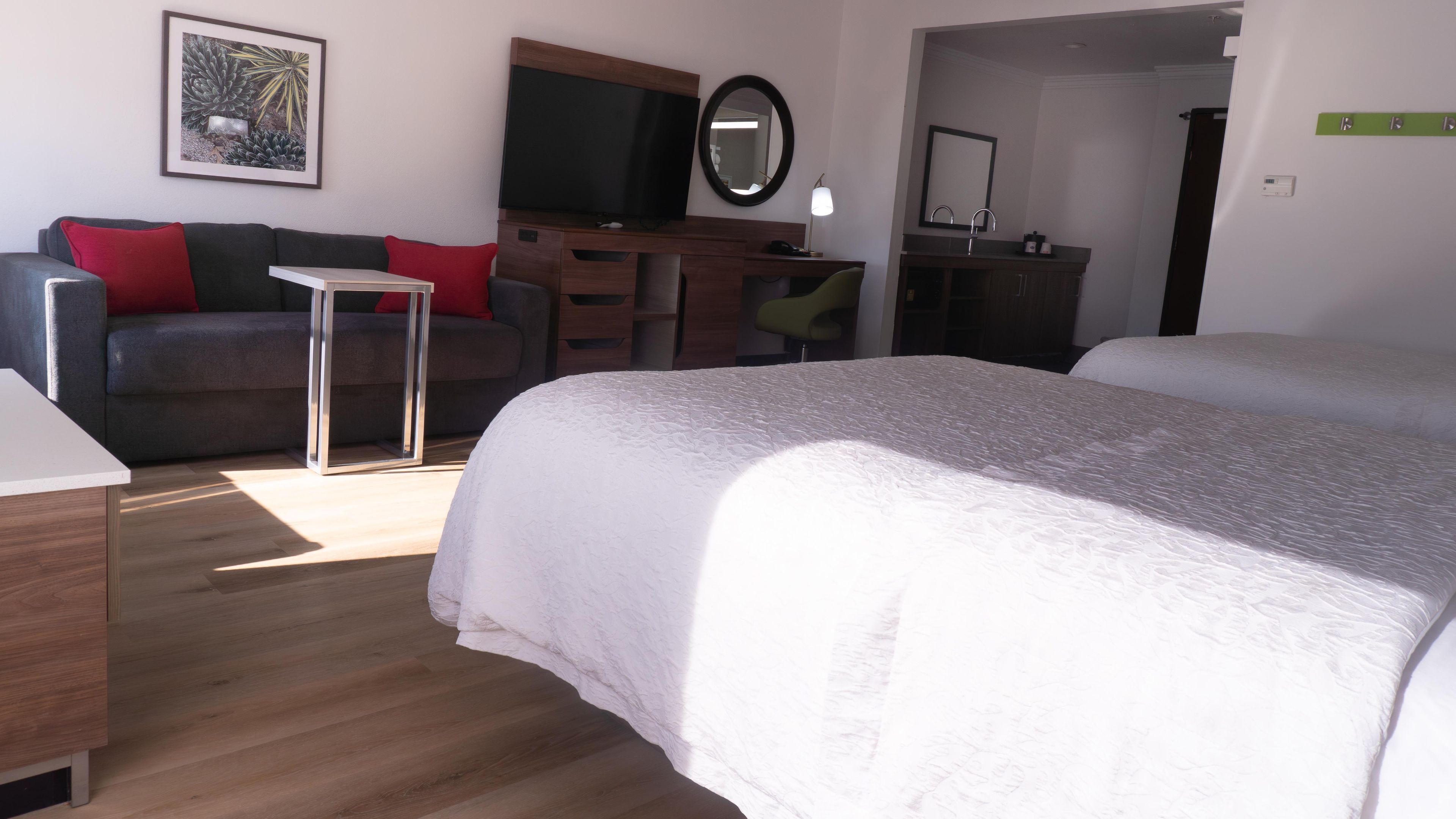 Habitación de hotel con cama, escritorio, silla, televisor y baño.